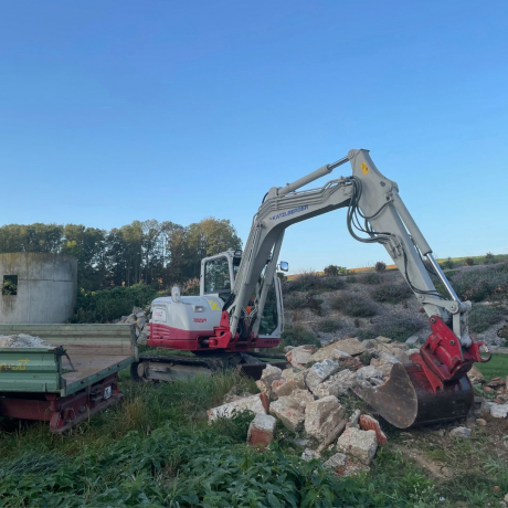 Ein roter Bagger der Marke Takeuchi führt Abbrucha